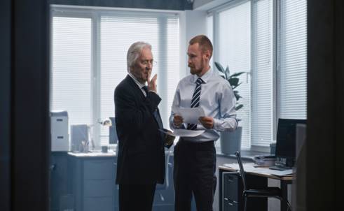 Older man looking at papers with coworker - Wrongful Termination